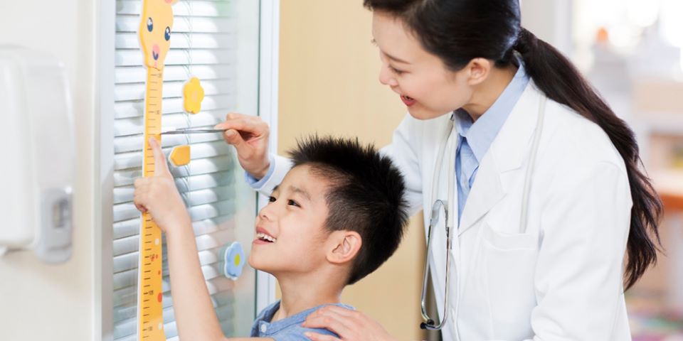 Médica medindo criança com curva de crescimento