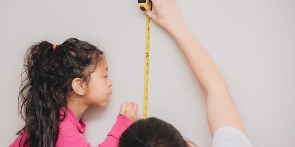 Mulher medindo uma criança com fita métrica
