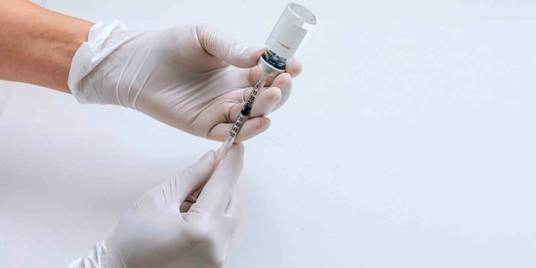 Profissional de saúde segurando seringa e ampola de vacina