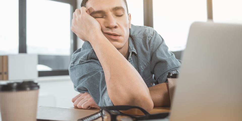 Homem dormindo apoiado na mesa