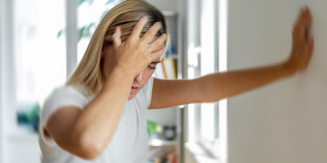 Mulher apoia a cabeça com a mão com expressão de dor