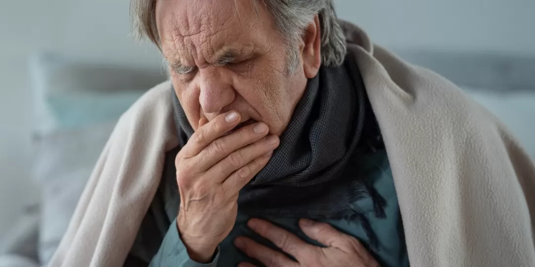 Homem idoso com mão na boca e peito e expressão doente