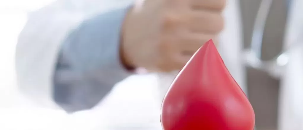 Gota de Sangue e um profissional de saúde fazendo sinal com a mão arás 