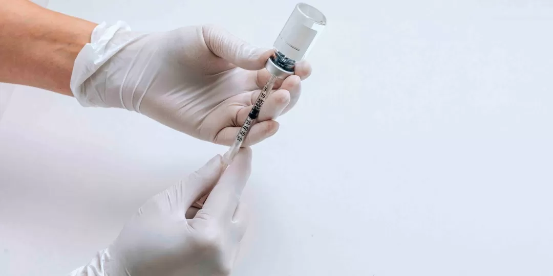 Profissional de saúde segurando seringa e ampola de vacina