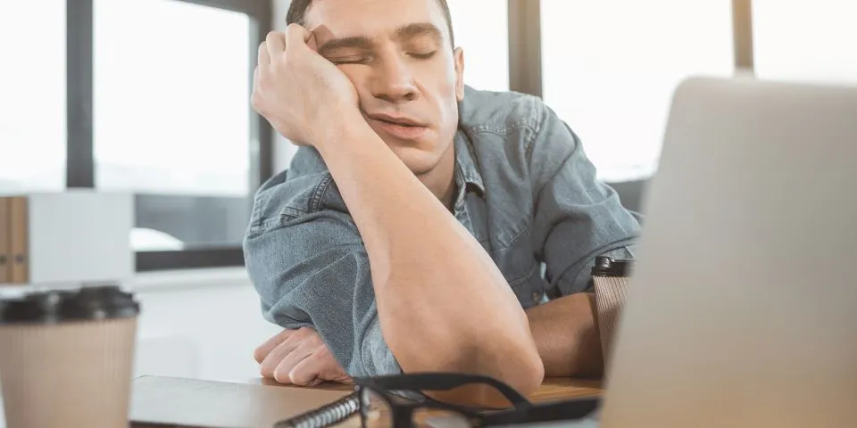 Homem dormindo apoiado na mesa