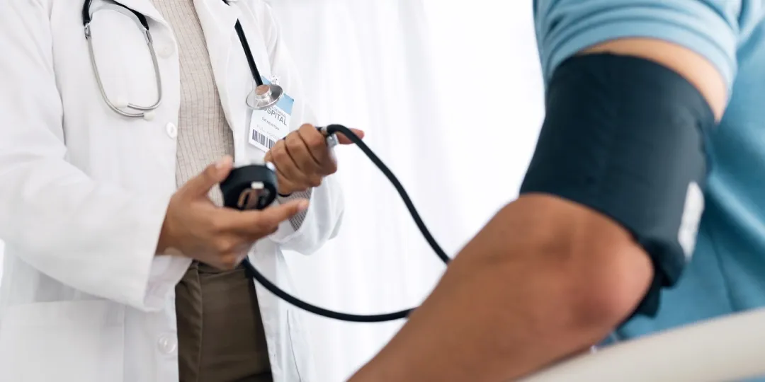 Homem tem a pressão arterial checada por profissional da saúde
