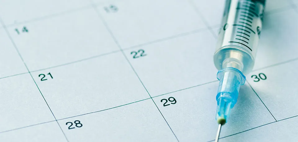Seringa de vacinação sobre um calendário